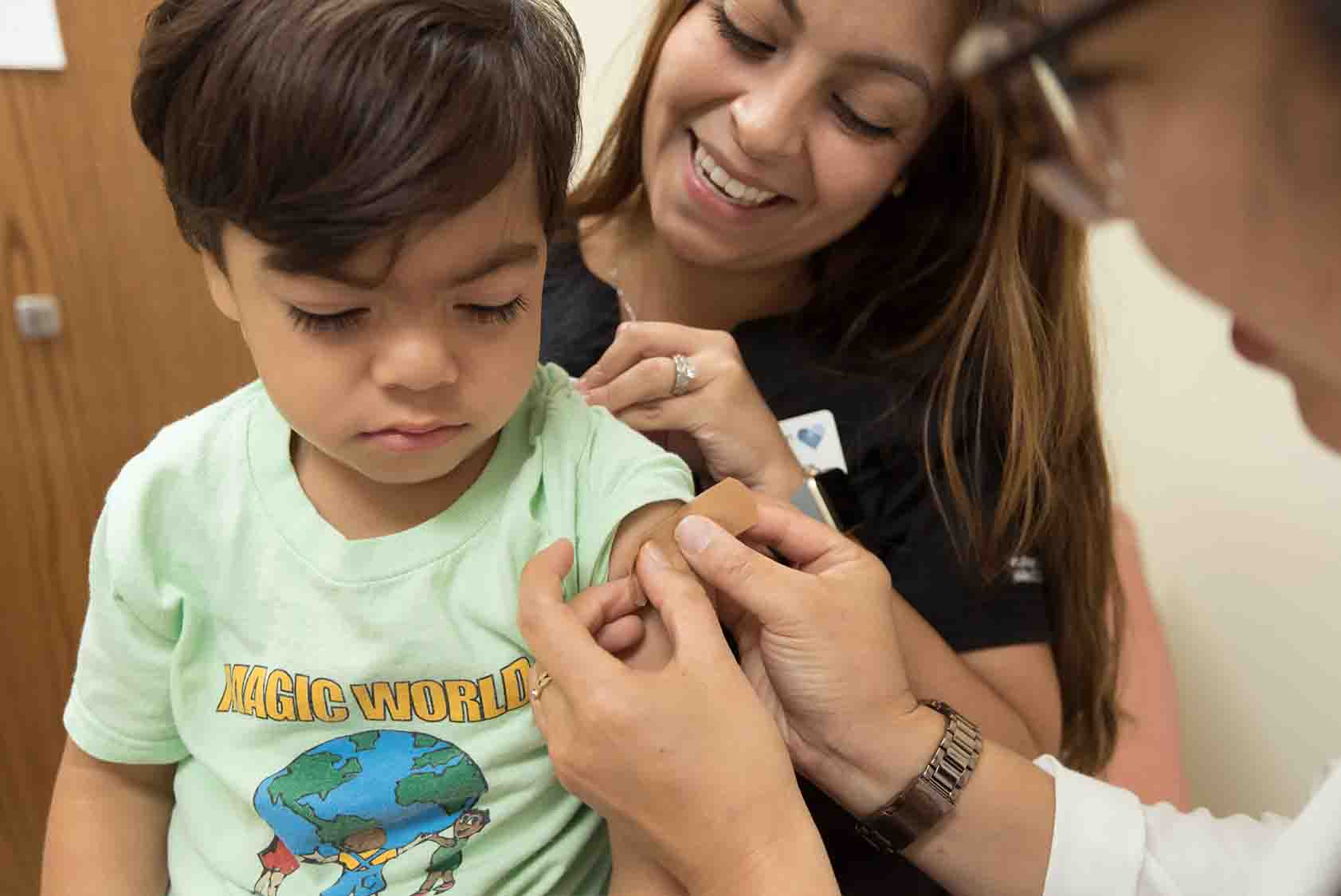 Doctor putting a bandaid on a child in a mother's lap